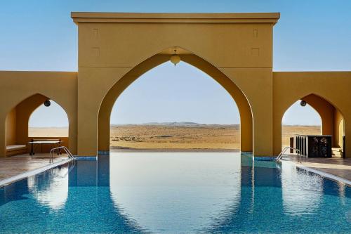 a swimming pool in the middle of a desert at Aldhafra Desert Resort, Vignette Collection by IHG in Madīnat Zāyid