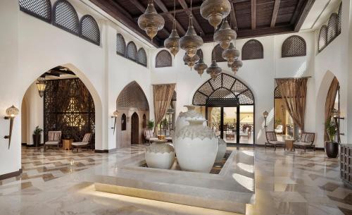 a lobby with two large white vases in the middle at Aldhafra Desert Resort, Vignette Collection by IHG in Madīnat Zāyid