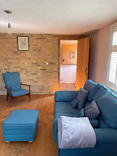 a living room with a blue couch and a chair at The stable near the business park tube Harry Potter airports in Croxley Green