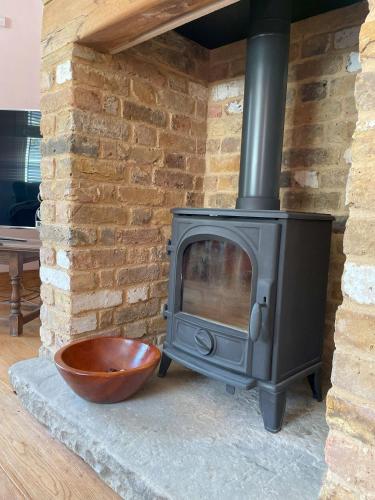a stove with a bowl next to a brick wall at The stable near the business park tube Harry Potter airports in Croxley Green