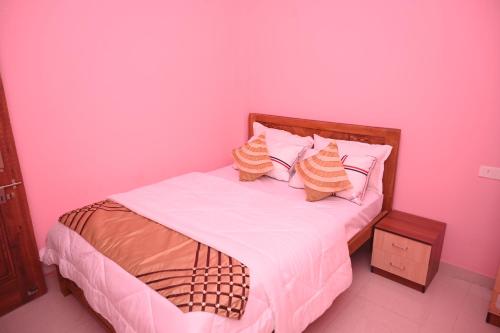 a pink bedroom with a bed with two pillows at Moon Guest House in Bhubaneshwar