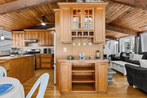 a kitchen with wooden cabinets and a living room at 10 Bunker Circle Sandwich - The Clubhouse Retreat in Sandwich
