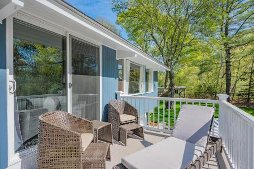 a screened porch with wicker chairs and a table at 10 Bunker Circle Sandwich - The Clubhouse Retreat in Sandwich