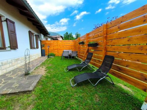 two chairs in the grass next to a fence at Apartma Pri noni Silvi in Tolmin
