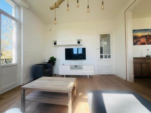 un soggiorno con un tavolo e una TV di La Villa Madeleine -jacuzzi - 10 voyageurs a Calais