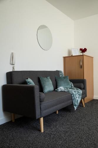 a gray couch with pillows in a living room at The Trafford Luxe , Garage Parking, Self Check-in Anytime - Perfect for Late Arrivals, Ultra- Fast Wi-Fi, 5 mins to Old Trafford Stadium in Manchester