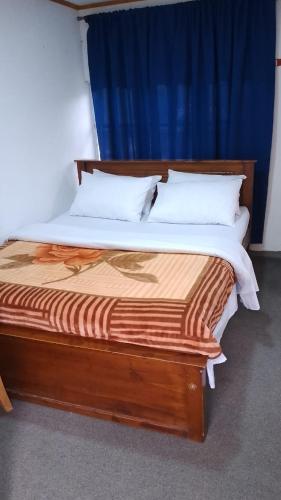 a bedroom with a wooden bed with two pillows at Misty Horizon Villa in Nuwara Eliya