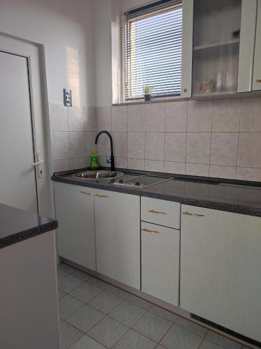 a kitchen with white cabinets and a sink at Studio apartman Trg in Županja