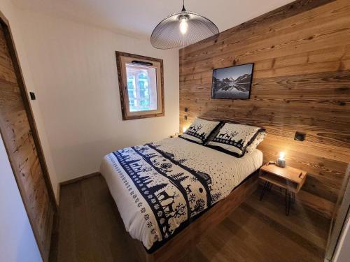 - une chambre avec un lit et un mur en bois dans l'établissement Appartement de charme au centre des Gets, proche pistes, 8 pers - moderne et équipé - FR-1-598-150, aux Gets