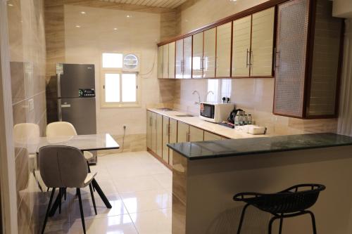 a kitchen with a counter and chairs and a refrigerator at جولدن هافن Golden Haven in Ahad Rafidah