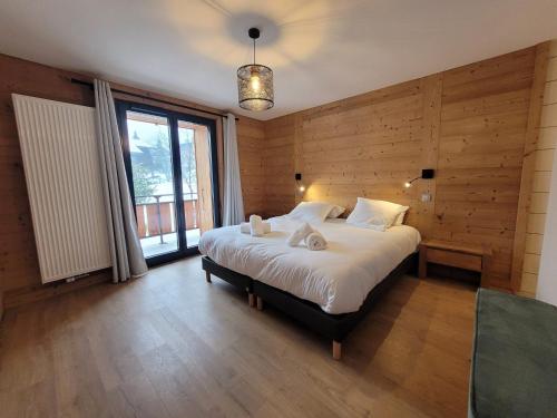 - une chambre avec un grand lit et des murs en bois dans l'établissement Appartement rénové, lumineux et calme, au centre des Gets, proche pistes et commodités - FR-1-598-158, aux Gets