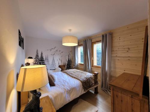 a bedroom with a bed and a lamp and a window at Appartement spacieux et lumineux, 3 chambres, proche centre Les Gets, terrasse, parking, calme. - FR-1-598-167 in Les Gets