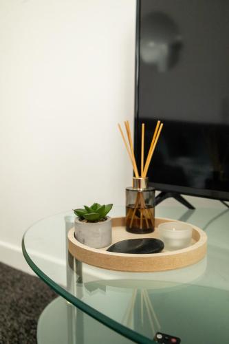 a glass table with a tv and plants on it at The Trafford Luxe , Garage Parking, Self Check-in Anytime - Perfect for Late Arrivals, Ultra- Fast Wi-Fi, 5 mins to Old Trafford Stadium in Manchester