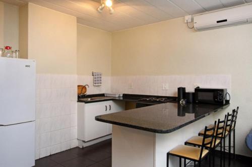a kitchen with white appliances and a black counter top at Vetho 2 Apartments OR Tambo Airport in Kempton Park