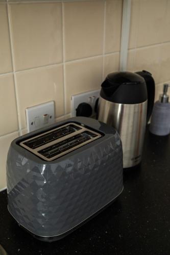 a toaster sitting on a counter next to a coffee pot at The Trafford Luxe , Garage Parking, Self Check-in Anytime - Perfect for Late Arrivals, Ultra- Fast Wi-Fi, 5 mins to Old Trafford Stadium in Manchester