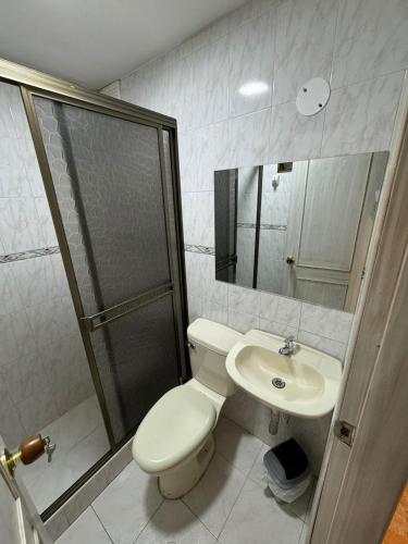 a bathroom with a toilet and a shower and a sink at Gato Neon Hostel in Bogotá