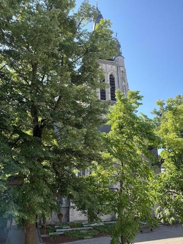 a building with a tower with a tree in front of it at Maison Martin 7 in Kortrijk