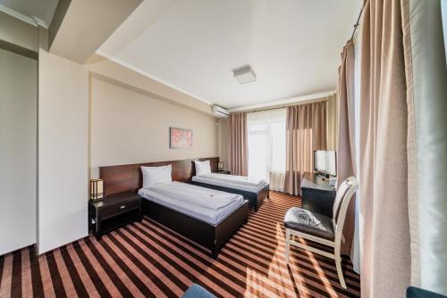 een hotelkamer met twee bedden en een stoel bij Pensiunea Belanco in Arad