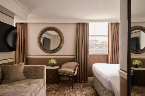a hotel room with a bed and a chair and a mirror at The Montague On The Gardens in London