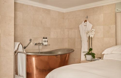 a bathroom with a tub next to a bed at The Montague On The Gardens in London
