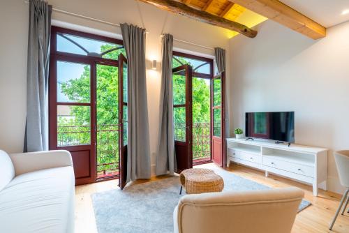 a living room with a couch and a tv and windows at Plaza Apartments by HostWise in Guimarães