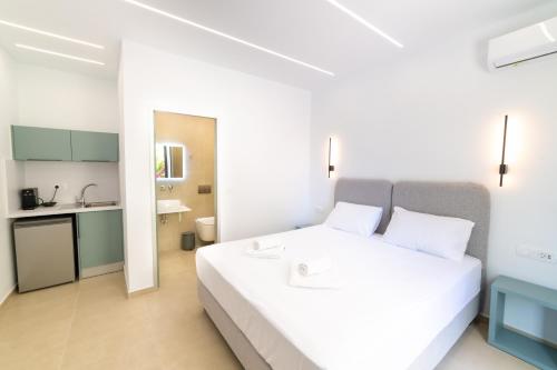 a bedroom with a white bed and a kitchen at Lithitsa Lofts and Suites in Parga
