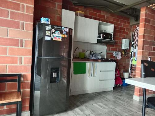 a kitchen with a refrigerator and a brick wall at Study by Los Molinos in Estación El Salto