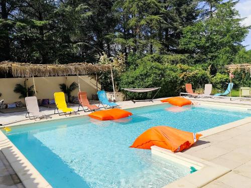 une grande piscine avec chaises et parasols dans l'établissement Ile des Plaisirs, Chambres d'Hôtes Naturistes avec Petit-Déjeuner Tropical Inclus, à Graulhet