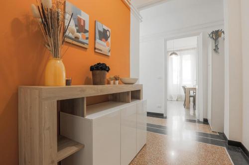 a kitchen with an orange wall and white cabinets at Un nido a Boccadasse in Genova