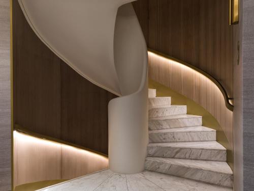 a spiral staircase in a lobby with a white column at Anthology of Athens, The Leading Hotels of the World in Athens