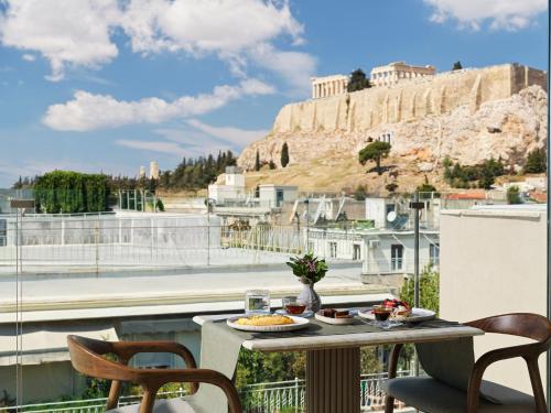 a balcony with a table and chairs and a view of the acropolis at Anthology of Athens, The Leading Hotels of the World in Athens