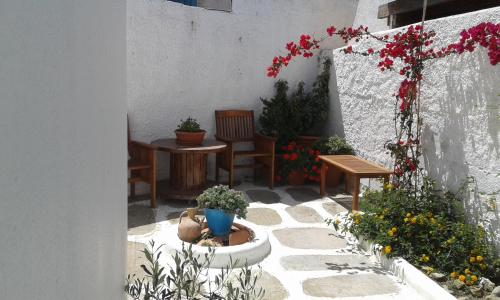 a patio with a table and chairs and flowers at Angela's Rooms in Mikonos