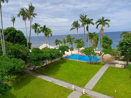 a park with a swimming pool and palm trees and the ocean at Dhauteya Villa in Amed