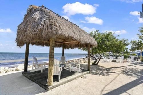 a straw umbrella and chairs on the beach at KAWAMA J3 in Key Largo, Beach, Lagoon, Pools, Tennis, Free Bikes and Canoes in Key Largo