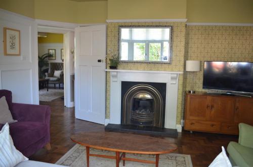 a living room with a fireplace and a tv at Lily House in Minehead