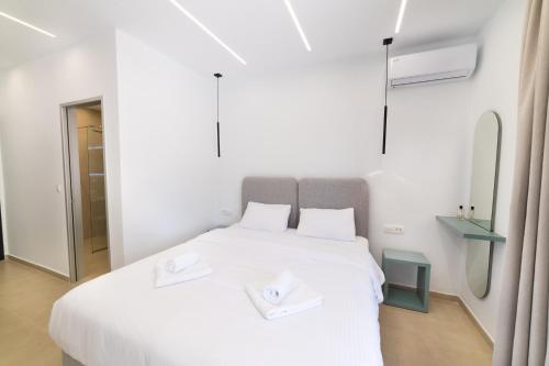 a bedroom with a white bed with two white towels on it at Lithitsa Lofts and Suites in Parga