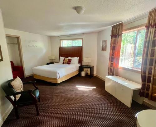 a bedroom with a bed and a chair and window at Saco River Motor Lodge & Suites in Center Conway