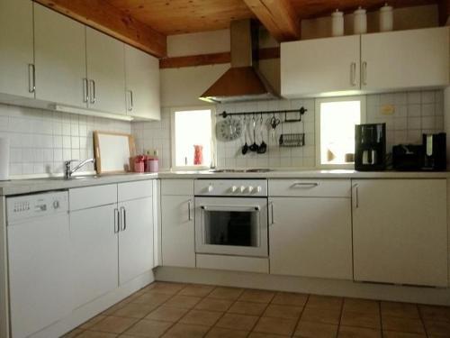 NorderfriedrichskoogReetdachhaus Für Erholsamen Familienurlaub的厨房配有白色橱柜和炉灶烤箱