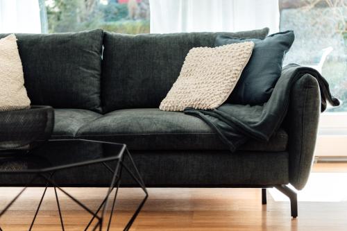 a green couch with pillows on it in a living room at Feel Home Apartments 701 - Seesicht - Terrasse - Parkplatz in Emmetten
