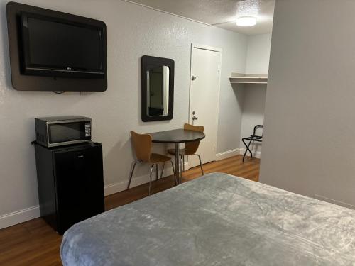 a room with a bed and a television and a table at Motel 6 - Pensacola West in Pensacola