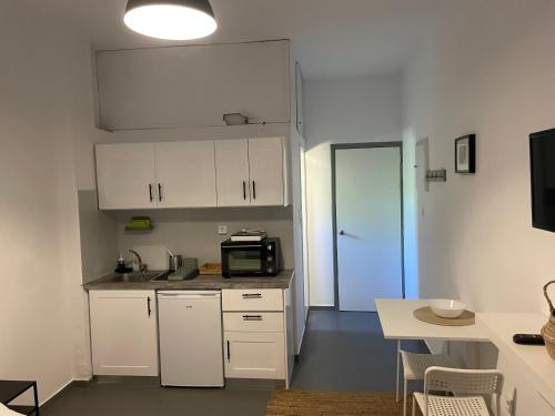 a small kitchen with white cabinets and a microwave at Spanos Studios - Panteli in Panteli