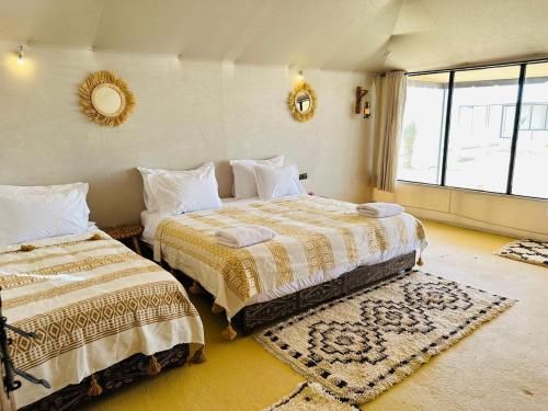 a bedroom with two beds and a large window at Merzouga Top Luxury Camp in Merzouga