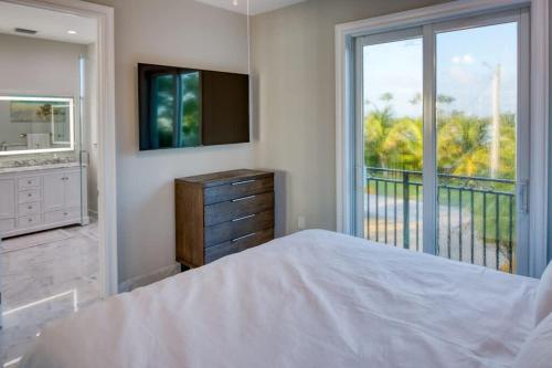 a bedroom with a bed and a television and a balcony at Luxurious Key Largo Oceanfront 3 Bed 3 5 Bath suite in Jewfish