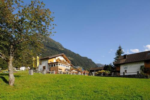 a green field with buildings and a tree in the foreground at Ruhige Wohnung In Sankt Gallenkirch Mit Garten in Sankt Gallenkirch
