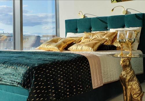 a bed with gold pillows and a table with glasses on it at Diamond class 2 Hanza Tower in Szczecin