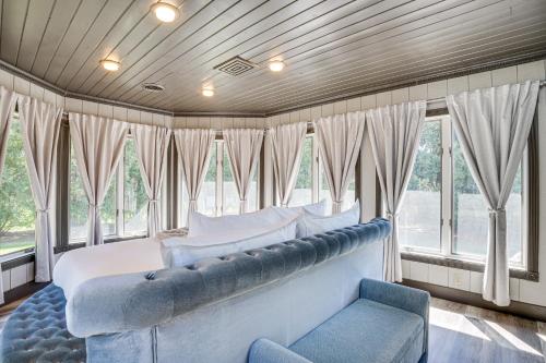 a bedroom with a bed and a couch and windows at 9 Mi to Shore Home with Hot Tub in Howards Grove! in Howards Grove