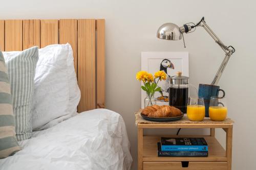 a bed with a night stand with a plate of bread and orange juice at Charming 2 Bedroom Apartment in a Converted Chapel - Free Parking, Smart TV, Fast WiFi and Self-Check-In by Yoko Property in St Asaph