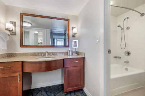 a bathroom with a sink and a tub and a mirror at Hilton Grand Vacations Club at Hilton Hawaiian Village in Honolulu