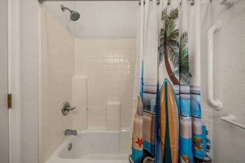 a bathroom with a bath tub with a shower curtain with surfboards at CR201 Salty Tides in Kill Devil Hills