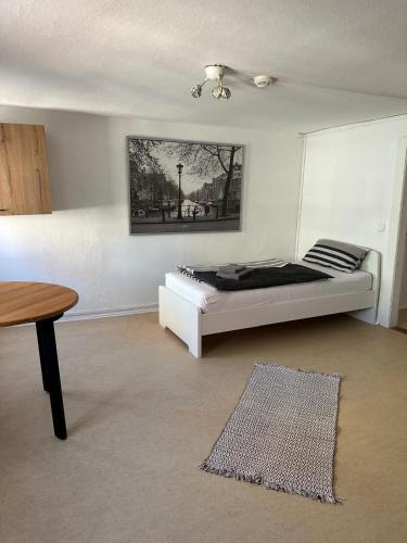 a white bedroom with a bed and a table at Denkerstraße in Rendsburg